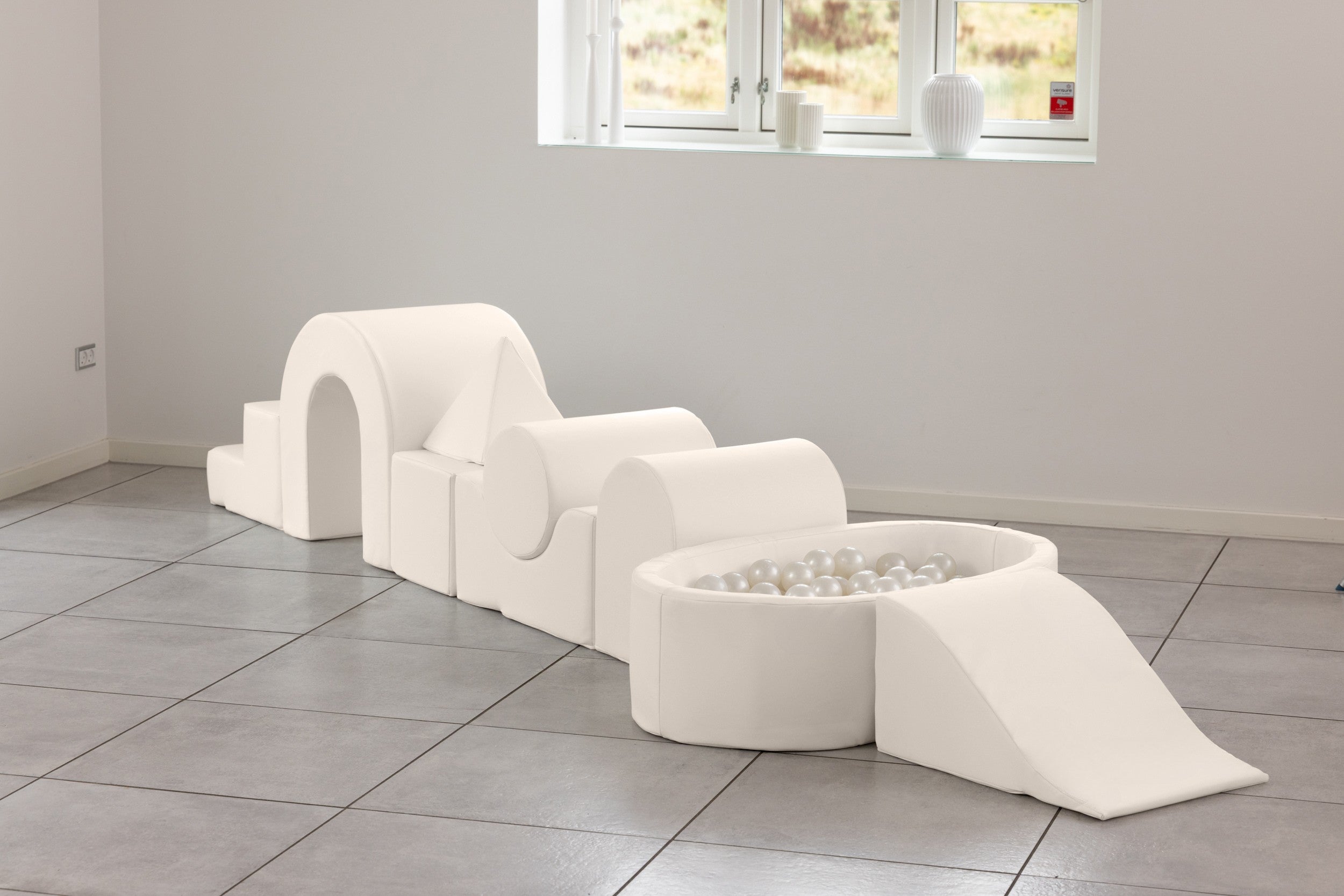 White modular play structure in a room with large windows.