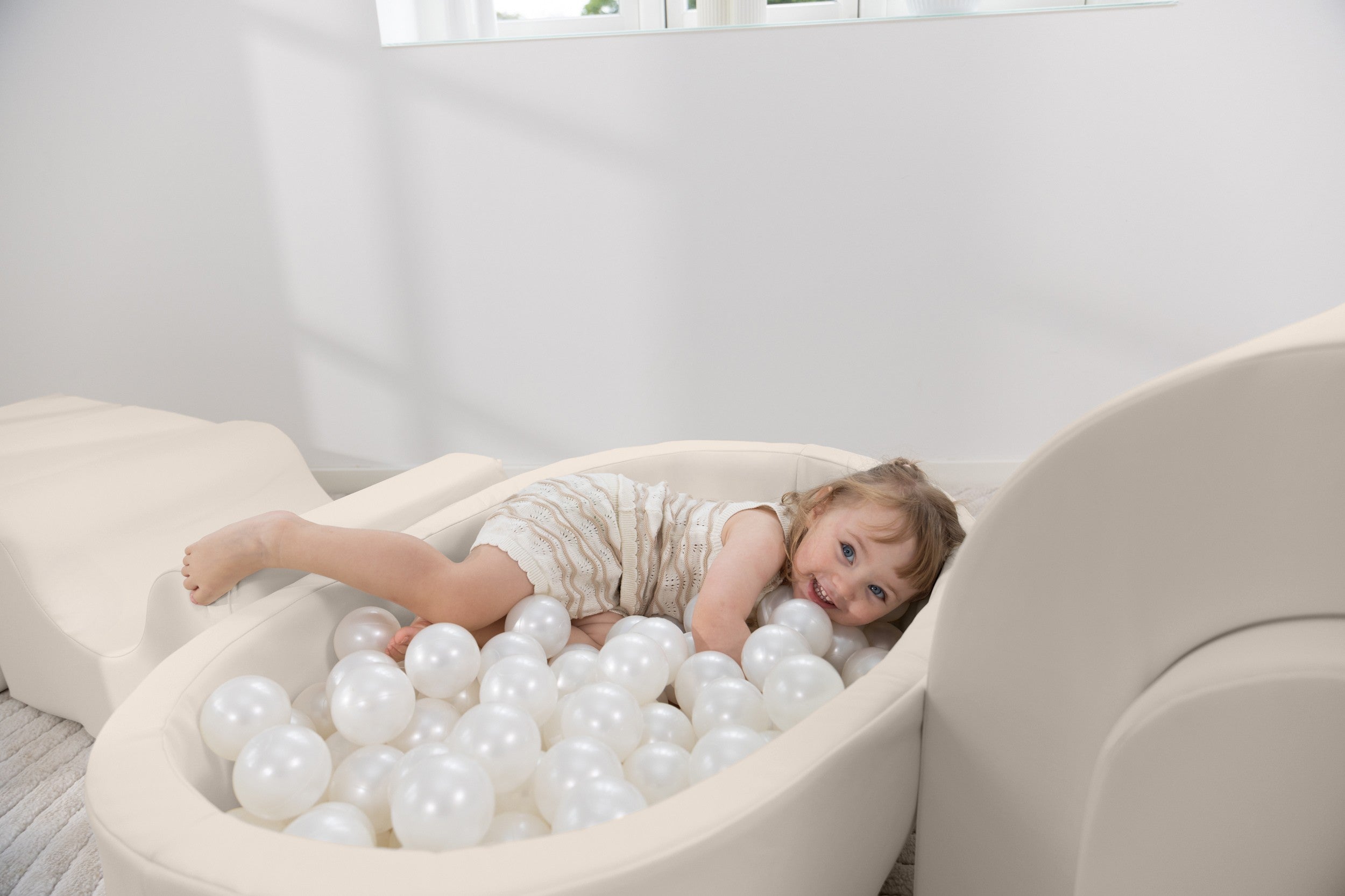 Child playing with white balls in a modern indoor setting