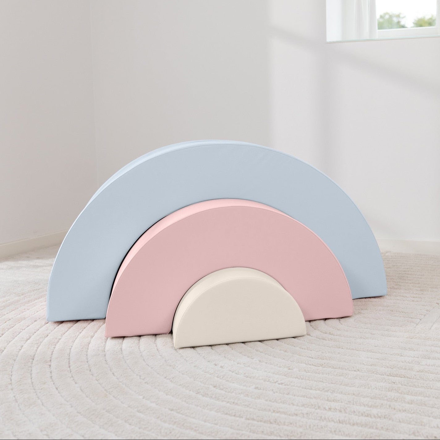 Pastel-colored rainbow-shaped blocks on a white surface with a window in the background